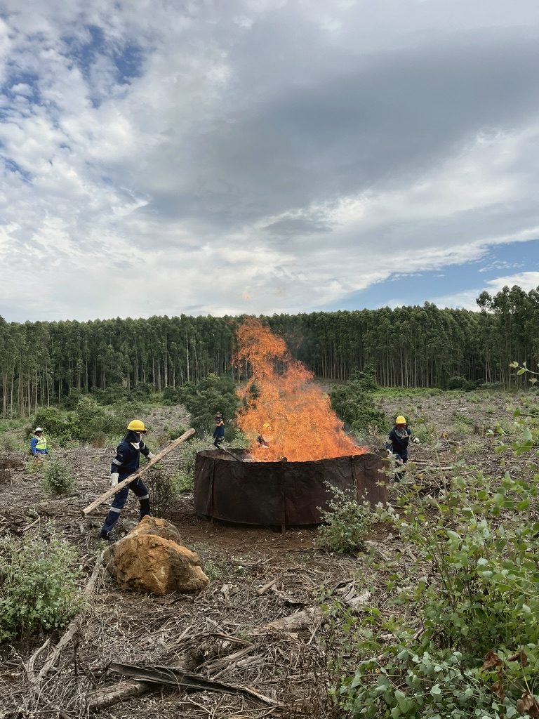 Kiln burning under a flame cap with a Blower Boss alongside